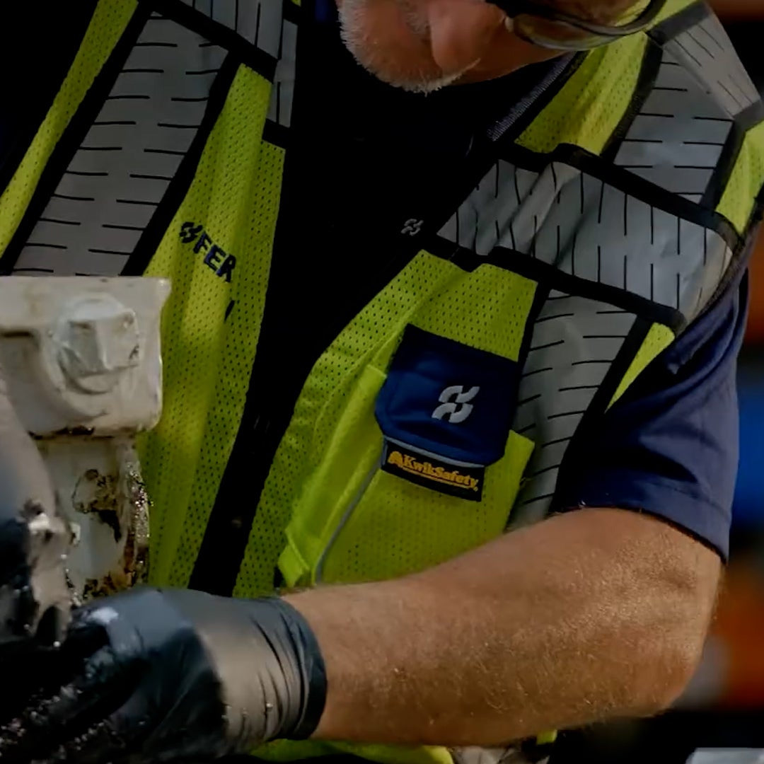 Hi Vis Customization - Person wearing a high-visibility vest and gloves working on a mechanical component.

